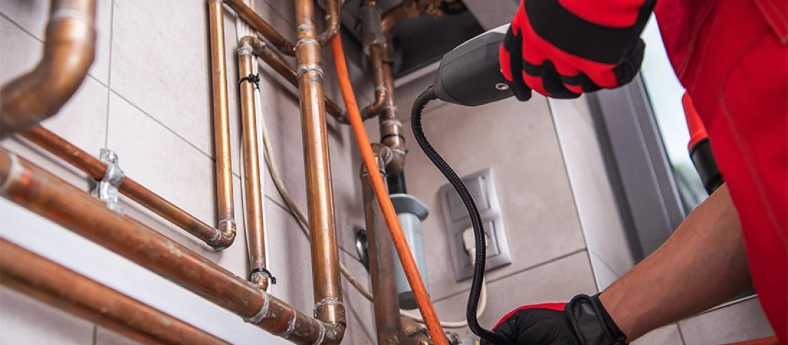 Technician with a gas leak detector standing next to pipes in an O’Fallon, IL home.